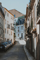 Naklejka premium People walking up a narrow cobblestone street in Lisbon