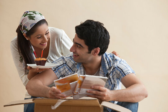 Young woman giving cupcake to man at home 