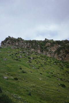 Green mountain slope with a rocky cliff