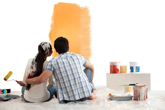 Loving young couple looking at sample paint together on wall 