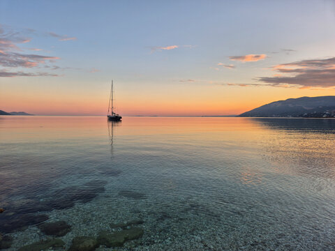 Serene sunset over Orikum beach with a sailboat in Vlor&euml;, Albania
