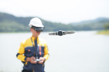Naklejka premium Engineer Operating Drone with FPV Goggles near Lake
