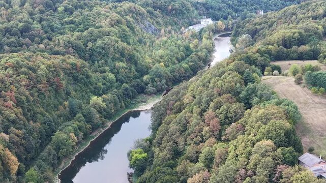 Aerial view of the Kupa river flowing through dense green forests and hills in Ozalj, Karlovac County, Croatia.