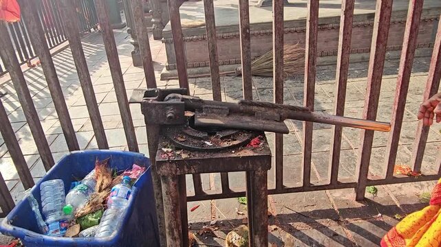 Close-up of a traditional coconut breaking tool used to crack coconuts for religious offerings at Mankamana Temple in Nepal. The scene shows traditional Hindu worship practices and temple rituals.