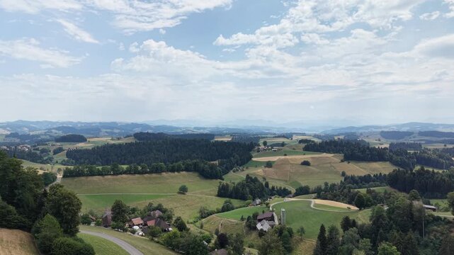 Aerial view of the rolling green hills, lush meadows, and dense forests of the rural landscape in Emmental District, Canton of Bern, Switzerland.