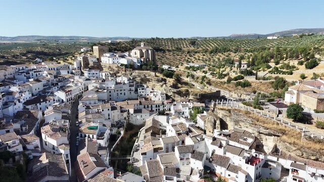 Aerial view of the white houses of Setenil de las Bodegas built into the rock cliffs with surrounding olive groves in Setenil de las Bodegas, Andalusia, Spain.