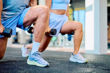 Fotobehang Sportschool Athletic man and woman training legs, performing lunge exercises with dumbbells at a modern fitness center  © we.bond.creations
