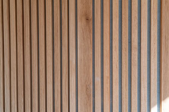 Vertical timber slat panelling with a tactile wood grain and blue acoustic backing, creating a calm textured surface for interior design and material libraries