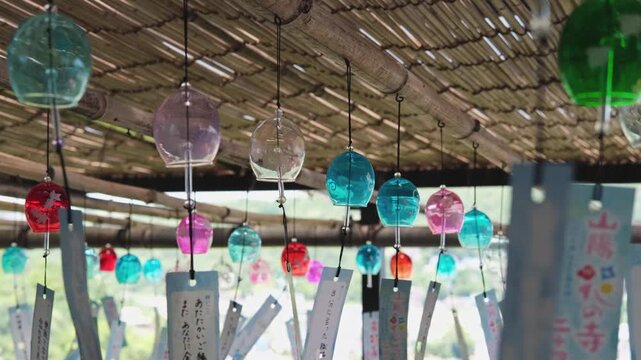 Colorful wind chimes hang beneath a thatched roof