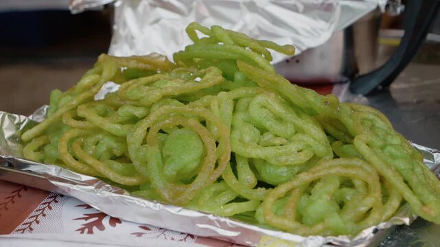 People gather at a street food market to taste green jalebi. This popular Indian dessert is made fresh and served warm during the festive celebration.