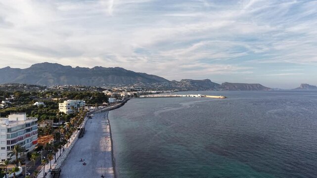 Aerial view of the coastal town of Altea with its pebble beach, palm-lined promenade, and mountains in the background in Altea, Valencian Community, Spain.