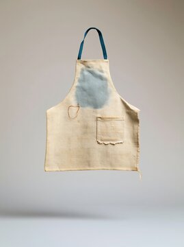 Repaired canvas work apron with a visible darning stitch and worn patina, featuring a neutral beige fabric and blue ties for a craft mockup