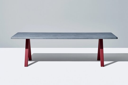 Rectangular dining table with a grey wooden top and red steel trestle legs, featuring a matte finish and contemporary style for furniture catalogues
