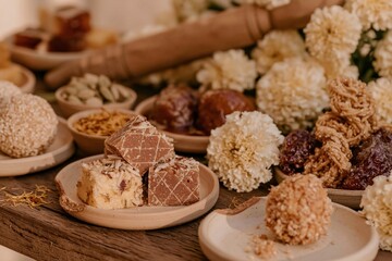 Fototapeta premium Traditional Indian sweets on a rustic red wooden table, featuring sticky syrups and crumbly textures for a festival food catalogue