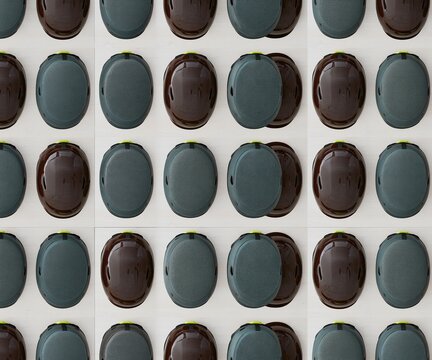Protective helmet shells in a symmetrical grid with high-gloss brown finishes and teal liners, arranged on a pale shelf for winter sports merchandising