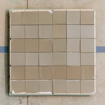 Flattened corrugated boxes stacked in an even grid on a pallet, featuring a matte fiber texture and torn tape for retail returns and logistics backgrounds