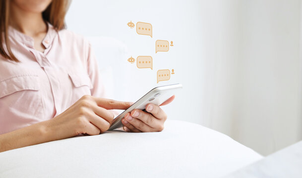 Woman using smartphone with AI chatbot speech bubble icons floating, representing customer support, digital communication and virtual assistant technology concept.