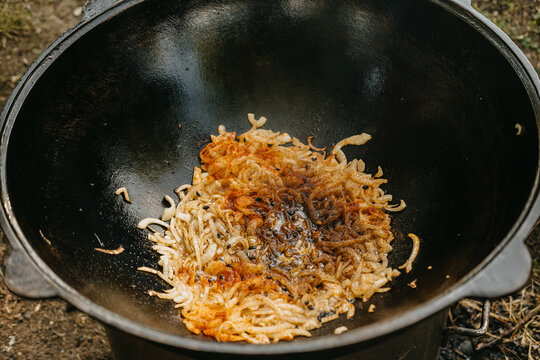 onions frying in a wok on a wooden surface in an outdoor cooking area with a warm and inviting top-down view.