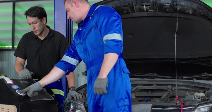 Auto mechanics servicing electric car air conditioning system with refrigerant recharge machine