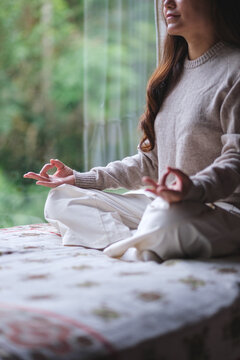 Vertical closeup of a woman meditating or practicing yoga in lotus pose on the bed
