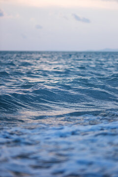 Vertical landscape image of sea wave splashing on beach before sunset