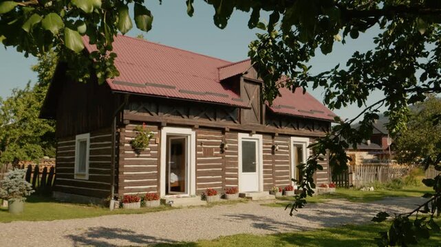 A traditional house in Bucovina sits surrounded by green grass and trees. The home features a wooden structure and bright white doors. This is a quiet time in the area.