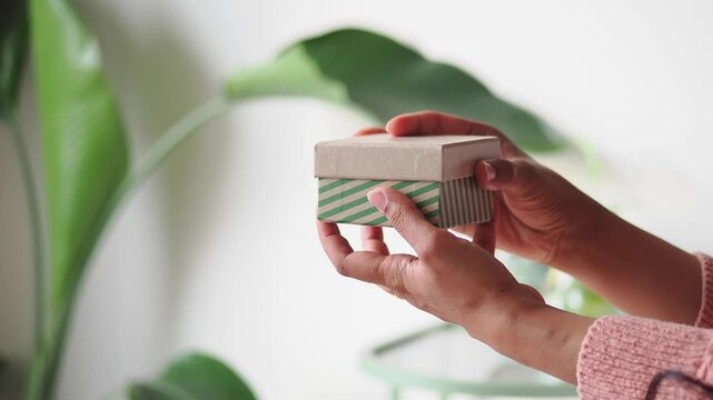 Person holds small gift box with green stripes in hand