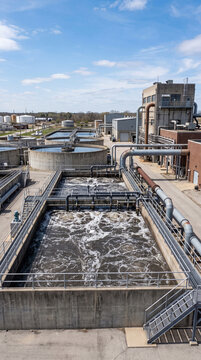 Industrial wastewater treatment plant with large concrete aeration tanks purifying liquid under blue sky