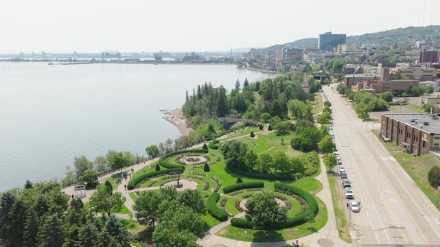 Aerial orbit view of Leif Erikson Park Rose Garden with circular flower beds along Lake Superior shoreline in Duluth