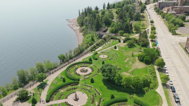 Aerial flyover of Leif Erikson Park Rose Garden along Lake Superior shoreline tilting up to reveal Duluth cityscape