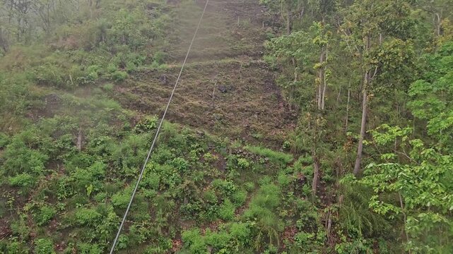 High-angle aerial view from the Manakamana cable car, looking down over dense green forest and rugged hillside terrain near the famous Manakamana Temple in Nepal.