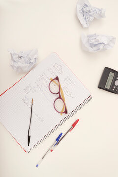 Student studying mathematics with crumpled paper and calculator