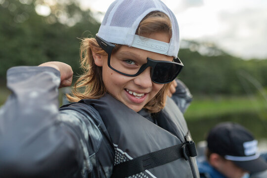 Smiling boy in sunglasses flexing on a boat