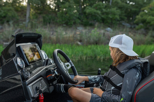 Young boy pretending to drive a fishing boat on a lake