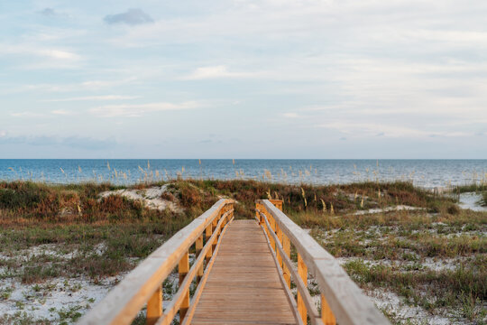 Wooden boardwalk leads over sand dunes to the ocean beach