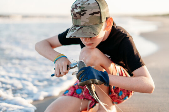 Young boy carefully removes a hook from a fish