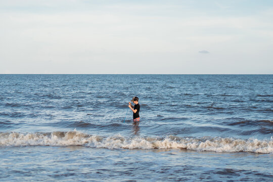 Young boy stands waist deep in the ocean