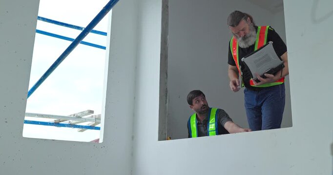 Construction worker measuring window opening with tape measure at house building site