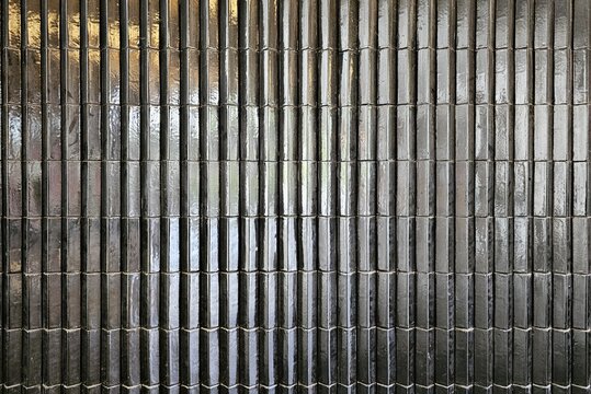 Glossy black tile vertical ribbed wall surface background for professional interior design presentation.