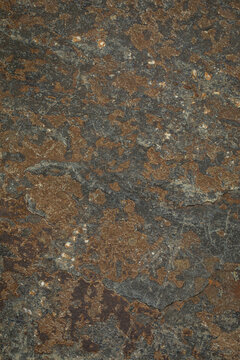 Natural rusty ironstone slate stone texture with rough mineral surface background. Weathered iron mineral deposits, dark grey slate layers, subtle cracks. Vertical image