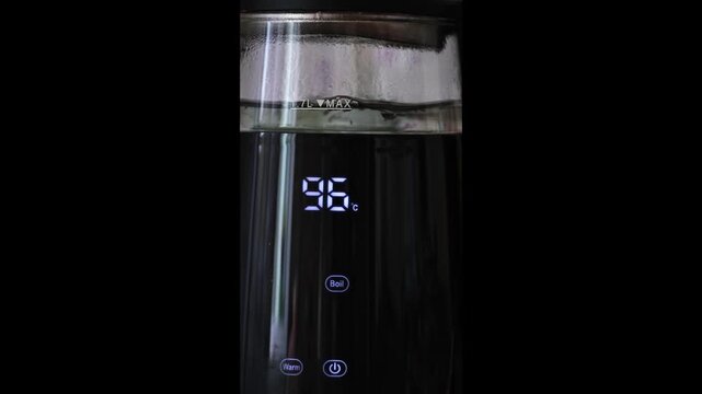 Modern electric kettle with digital display boils, showing increasing temperature rising to 100 degrees.