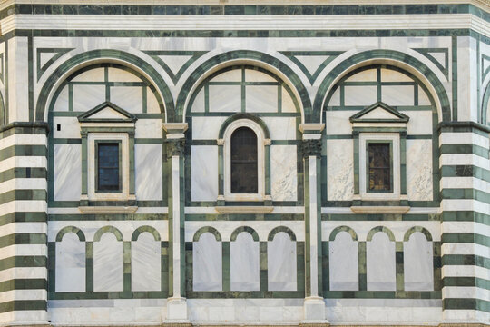 Detalle de la fachada de m&aacute;rmol blanco y verde con arcos y ventanas geom&eacute;tricas de arquitectura renacentista en Florencia.