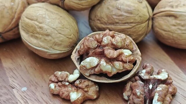  Walnut kernels and whole walnuts on wooden background
