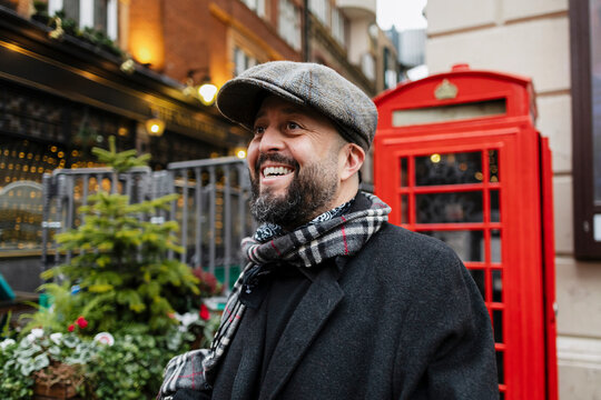 A smiling man in a flat cap enjoys a festive winter market