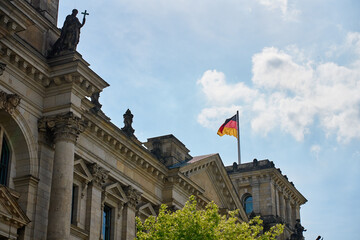 Fototapeta premium Reichstag building facade with waving German flag in Berlin, Germany