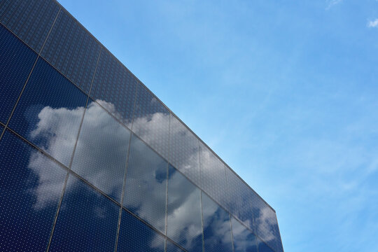 Modern glass building facade reflecting clouds