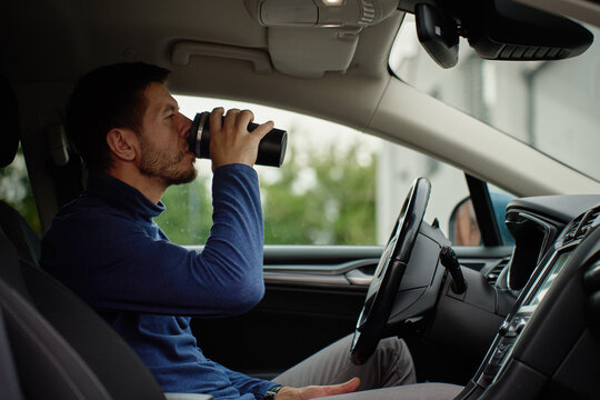Man drinking coffee while sitting in car