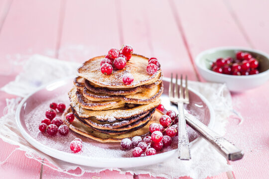 Stack of American pancakes with red currents sprinkled with icing sugar
