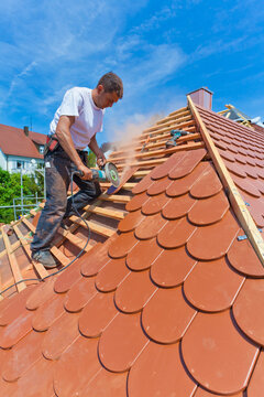 Germany, Baden-Wuerttemberg, Stuttgart, Mid adult man cutting roof tile