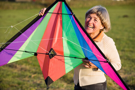 senior adult woman holding kite, smiling 